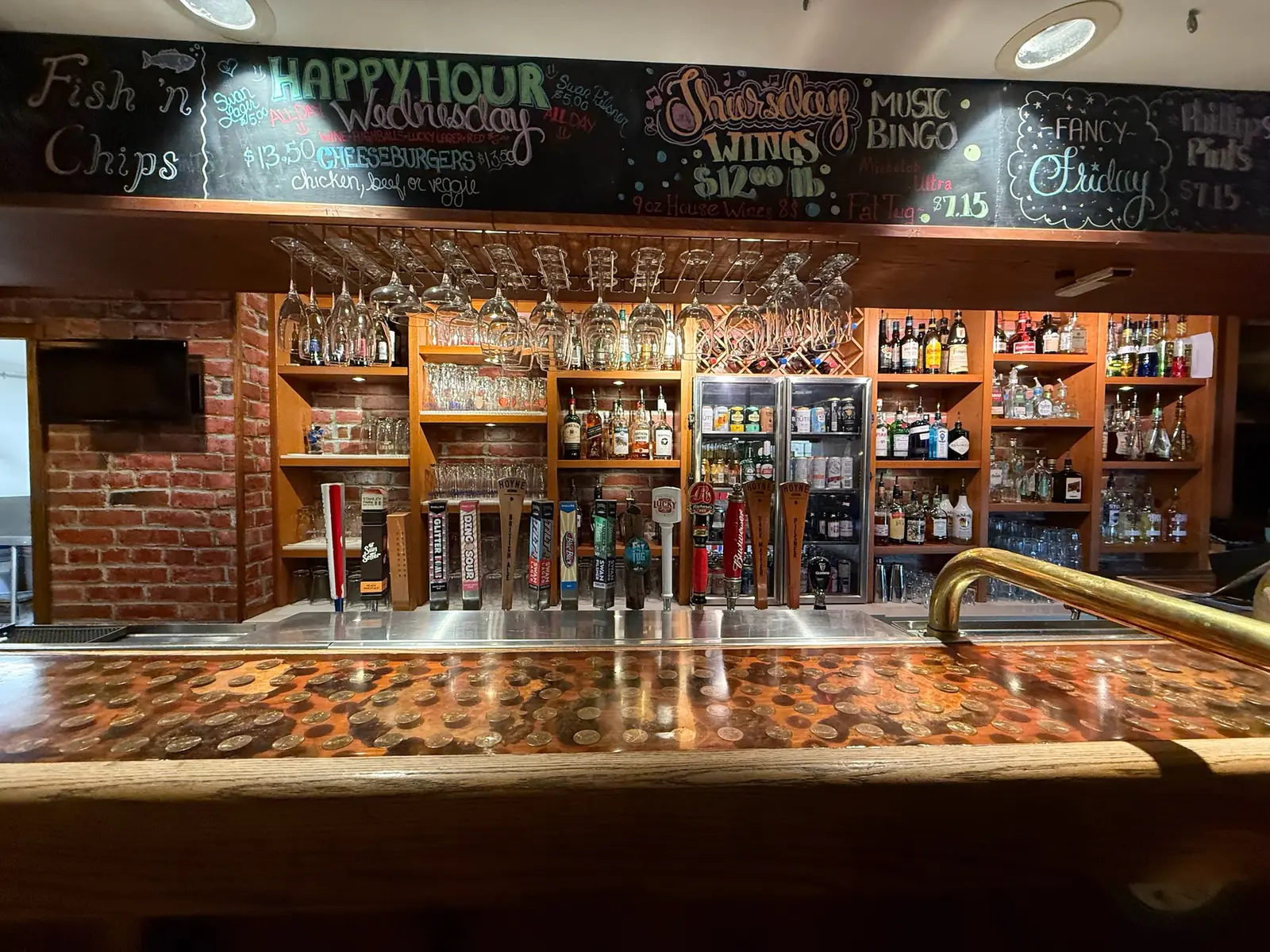 The copper penny bar top and tap wall at the Black Swan Pub in Shawnigan Lake, with the chalkboard of specials above it