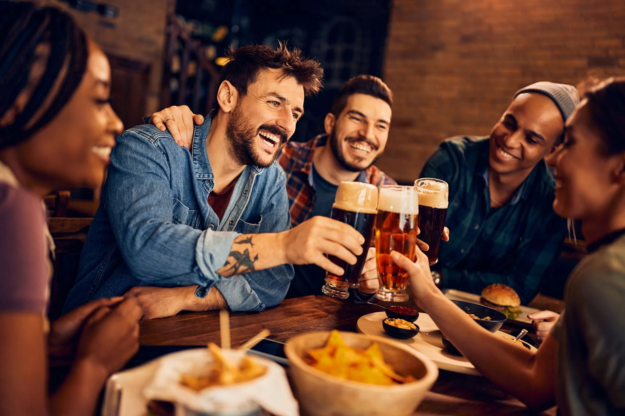 Friends raising pints together around a table at the Black Swan Pub